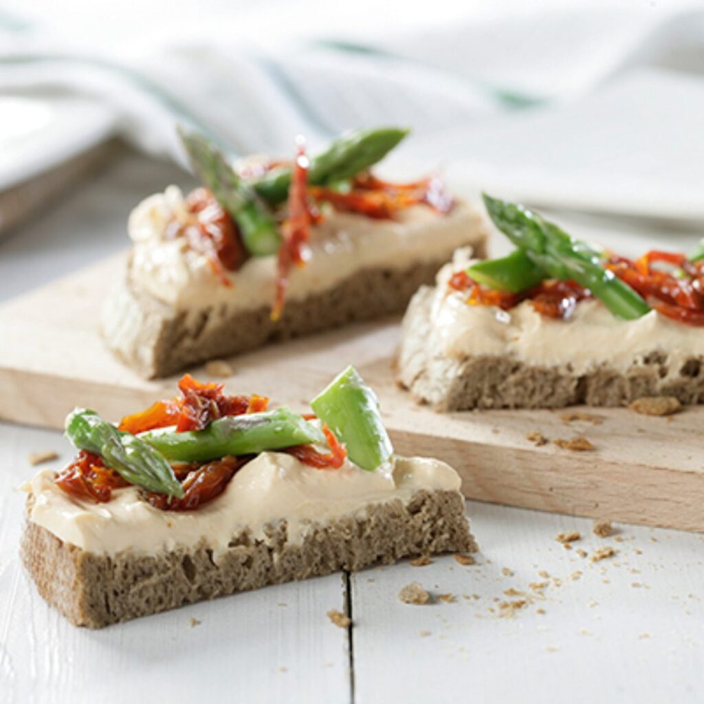 Tostas de pão de centeio com Philadelphia com salmão, espargos e tomates secos em azeite